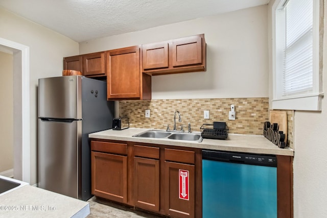 kitchen with appliances with stainless steel finishes, backsplash, a textured ceiling, and sink