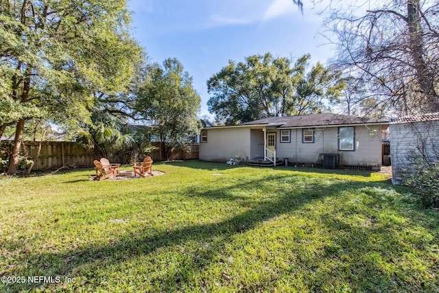 back of house with a lawn, central air condition unit, and an outdoor fire pit