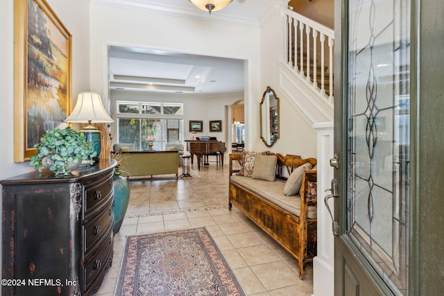 tiled entrance foyer featuring a raised ceiling and ornamental molding