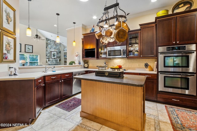 kitchen featuring kitchen peninsula, appliances with stainless steel finishes, decorative backsplash, ceiling fan, and a center island