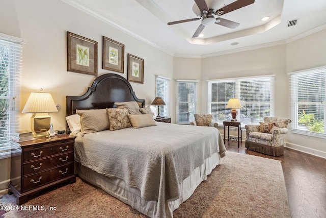 bedroom featuring dark hardwood / wood-style flooring, a tray ceiling, ceiling fan, and ornamental molding