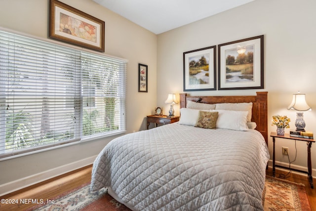 bedroom with dark hardwood / wood-style flooring and multiple windows