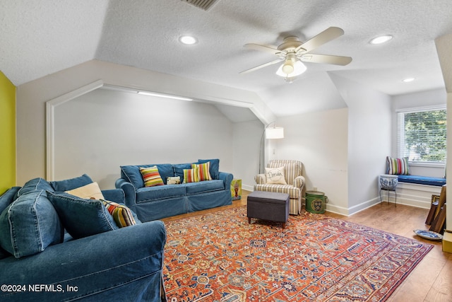 living room with wood-type flooring, a textured ceiling, vaulted ceiling, and ceiling fan