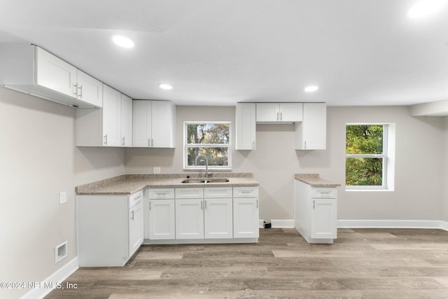 kitchen featuring white cabinets, light wood-type flooring, and sink