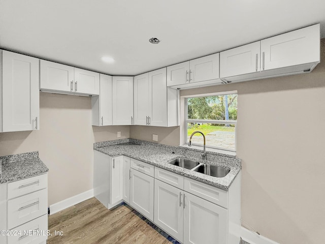 kitchen featuring white cabinets, light stone counters, and sink