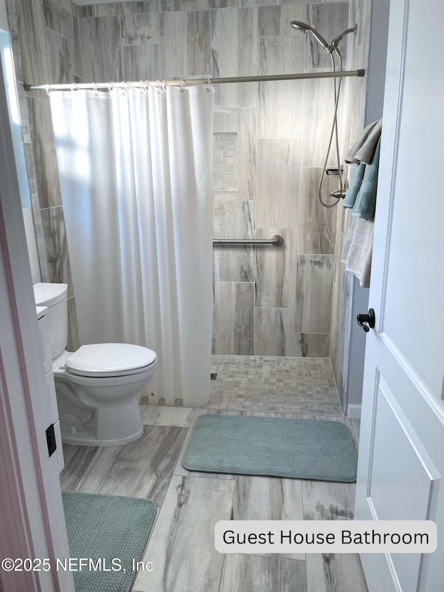 bathroom with hardwood / wood-style flooring, toilet, and walk in shower