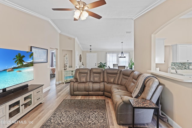 living room with ceiling fan, light wood-type flooring, crown molding, and vaulted ceiling