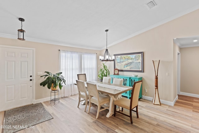 dining space featuring vaulted ceiling, light wood-type flooring, crown molding, and a chandelier