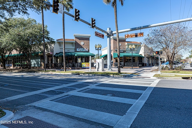 view of street with traffic lights, street lights, traffic signs, sidewalks, and curbs