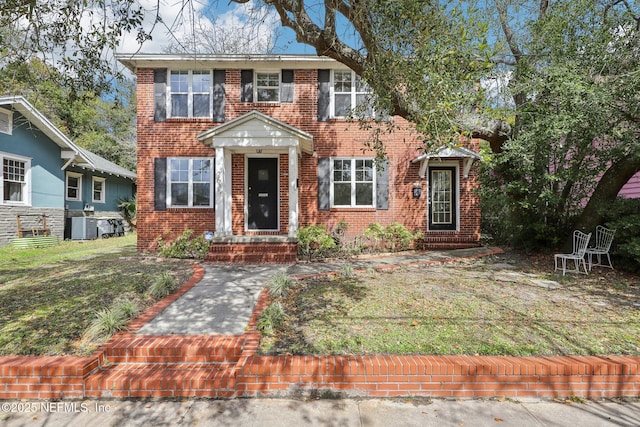 colonial inspired home with cooling unit and brick siding