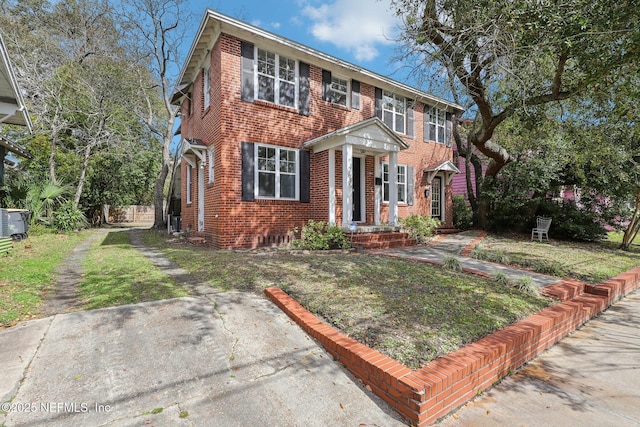 colonial inspired home featuring brick siding and a front lawn