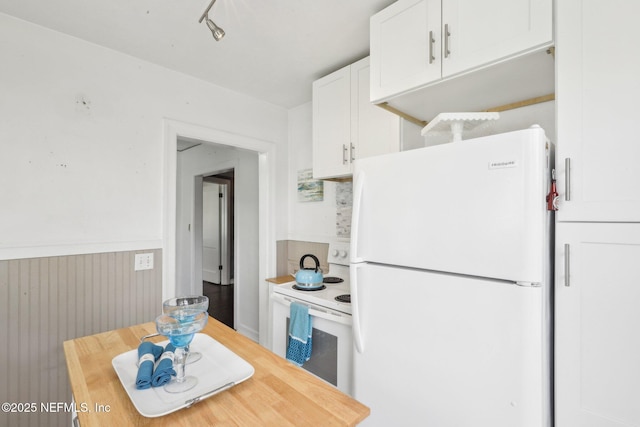 kitchen with white appliances, white cabinets, wooden counters, and a wainscoted wall