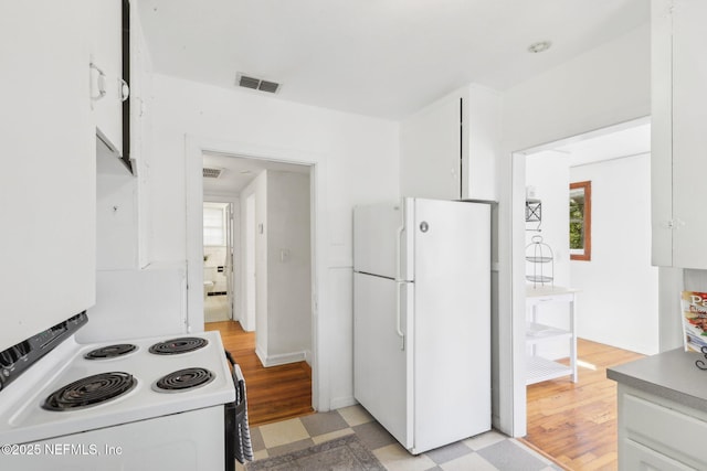 kitchen featuring white appliances, visible vents, white cabinets, and light floors