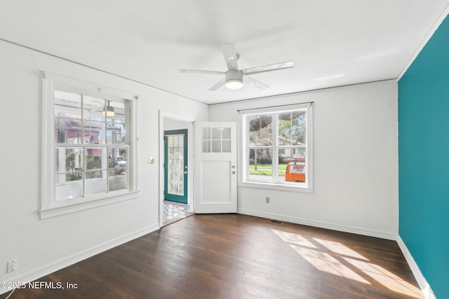 unfurnished room featuring baseboards, dark wood finished floors, and a ceiling fan