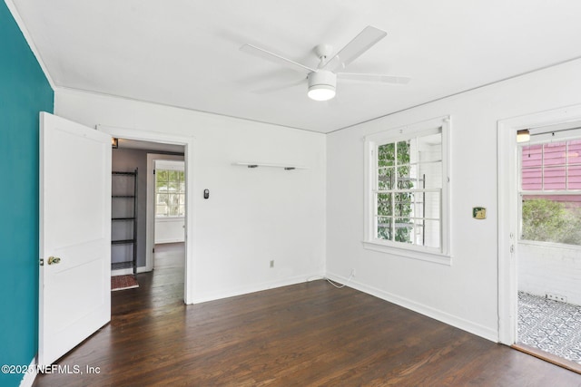 spare room featuring dark wood-style flooring, a healthy amount of sunlight, ceiling fan, and baseboards