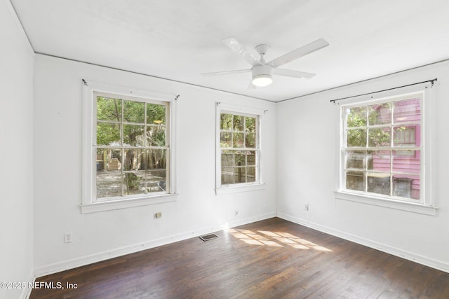 empty room with ceiling fan, dark wood-style flooring, visible vents, and baseboards