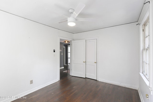 unfurnished bedroom with dark wood-style floors, baseboards, and a ceiling fan