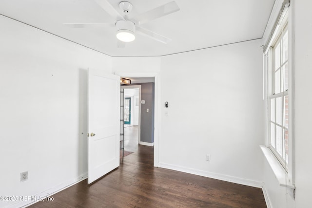 spare room with dark wood-style flooring, a ceiling fan, and baseboards