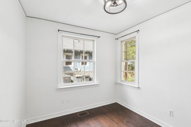 empty room featuring dark wood-style floors, baseboards, and visible vents