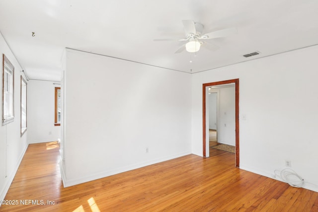 unfurnished room with a ceiling fan, visible vents, light wood-style flooring, and baseboards