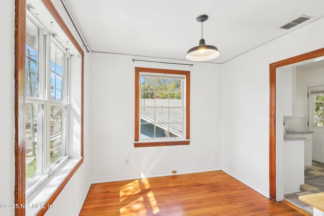 spare room with visible vents, plenty of natural light, light wood-style flooring, and baseboards