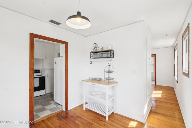 hall with light wood-type flooring, baseboards, and visible vents