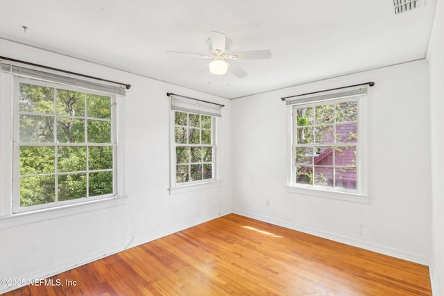 spare room with light wood-style floors, visible vents, ceiling fan, and baseboards