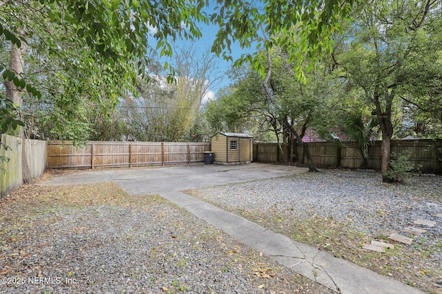 view of yard featuring a fenced backyard, a storage unit, a patio, and an outbuilding