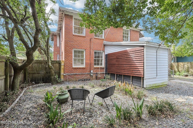 rear view of house featuring fence and brick siding