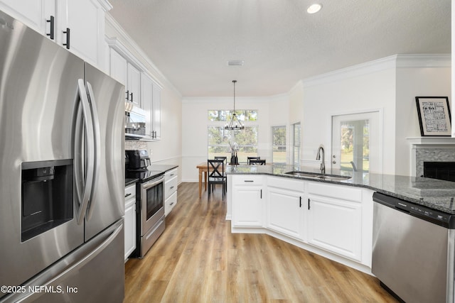 kitchen featuring white cabinets, hanging light fixtures, sink, appliances with stainless steel finishes, and a notable chandelier