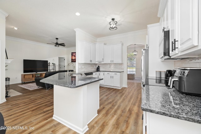 kitchen featuring ceiling fan, stainless steel appliances, kitchen peninsula, dark stone counters, and white cabinets