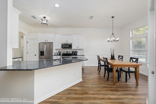 kitchen featuring appliances with stainless steel finishes, crown molding, sink, dark stone countertops, and white cabinetry