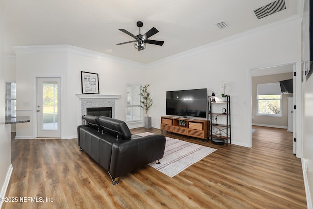 living room featuring hardwood / wood-style flooring, ceiling fan, and crown molding