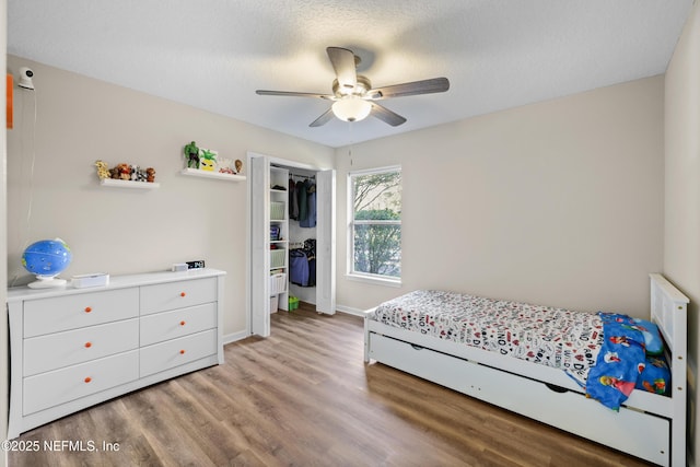 bedroom featuring a textured ceiling, a closet, light hardwood / wood-style flooring, and ceiling fan