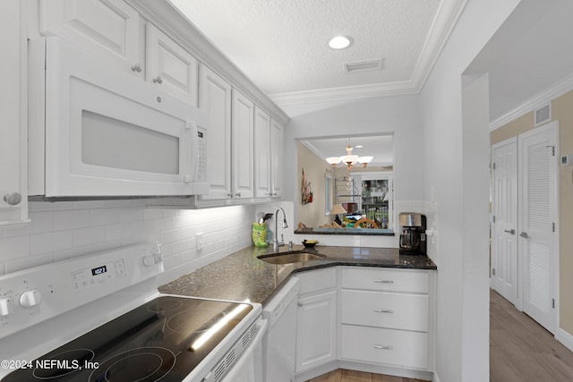 kitchen with a textured ceiling, white appliances, sink, a notable chandelier, and white cabinetry