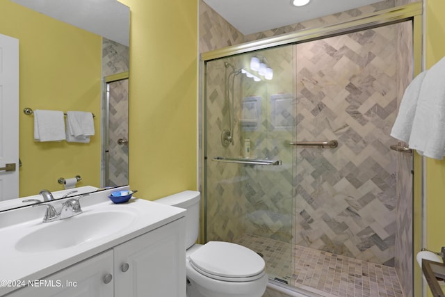 bathroom featuring vanity, a shower with shower door, and toilet