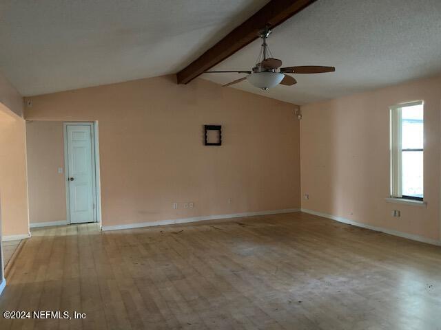 unfurnished room with ceiling fan, lofted ceiling with beams, and light wood-type flooring