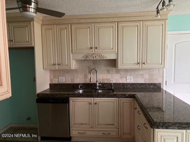 kitchen with dishwasher, sink, dark stone countertops, tasteful backsplash, and cream cabinetry