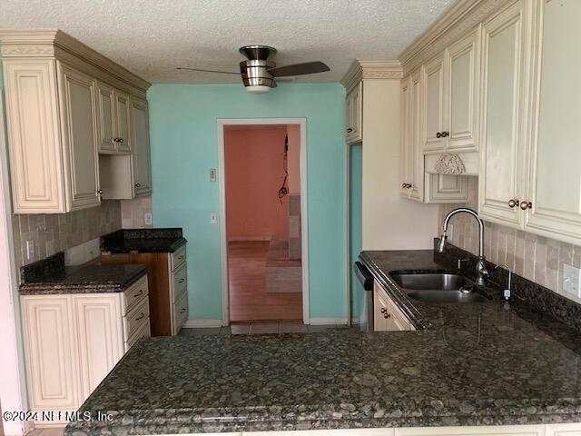 kitchen featuring kitchen peninsula, decorative backsplash, a textured ceiling, ceiling fan, and sink