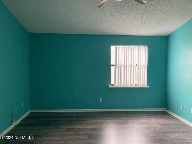 unfurnished room featuring a textured ceiling, ceiling fan, and dark wood-type flooring