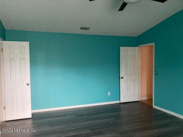 empty room with dark hardwood / wood-style flooring, vaulted ceiling, and ceiling fan