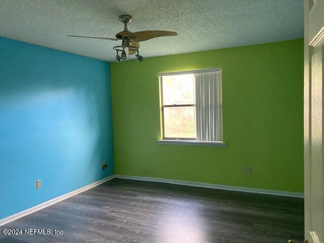 empty room featuring a textured ceiling, dark hardwood / wood-style flooring, and ceiling fan