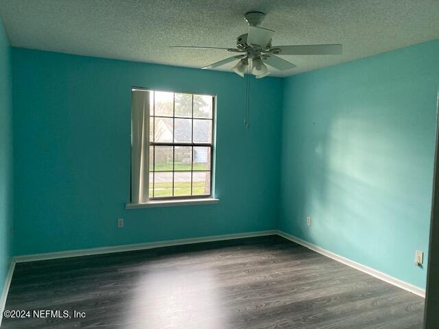 empty room featuring ceiling fan, dark hardwood / wood-style floors, and a textured ceiling