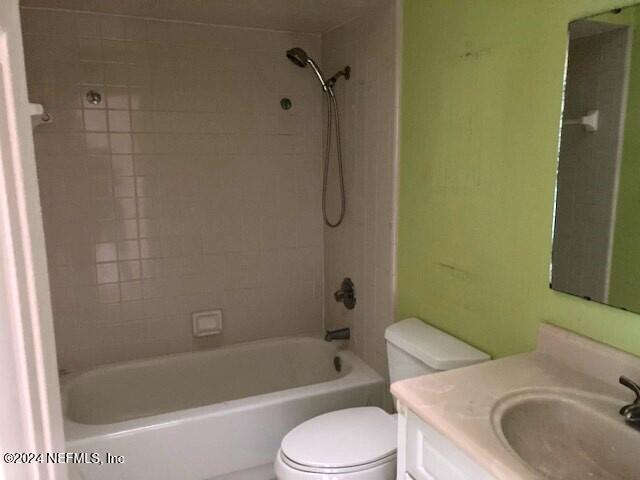 full bathroom with vanity, tiled shower / bath combo, and toilet