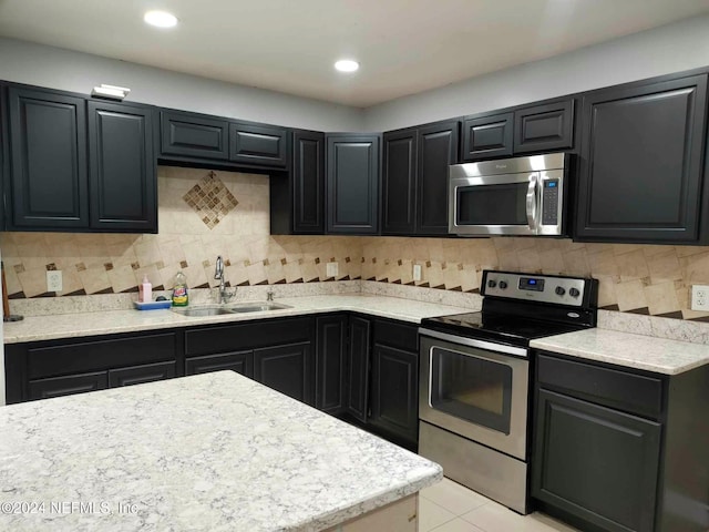 kitchen featuring stainless steel appliances, light countertops, decorative backsplash, a sink, and dark cabinets