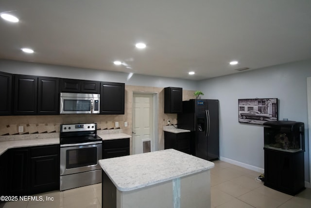 kitchen with stainless steel appliances, visible vents, light countertops, a kitchen island, and dark cabinets