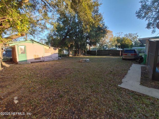 view of yard with an outbuilding, a fenced backyard, and a shed