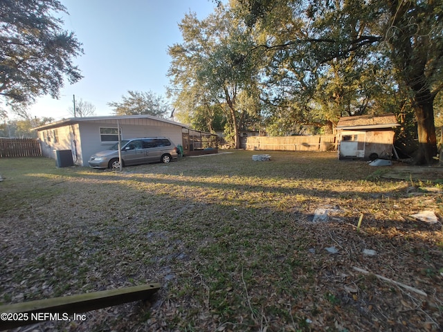 view of yard featuring central air condition unit, a storage unit, fence, and an outbuilding