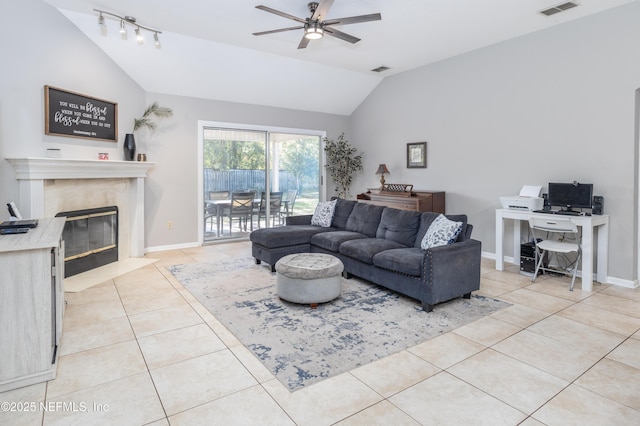 living room with ceiling fan, a fireplace, light tile patterned floors, and vaulted ceiling