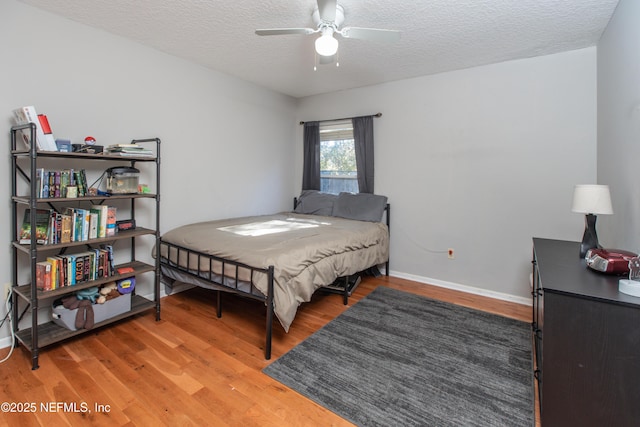 bedroom featuring ceiling fan, wood-type flooring, and a textured ceiling